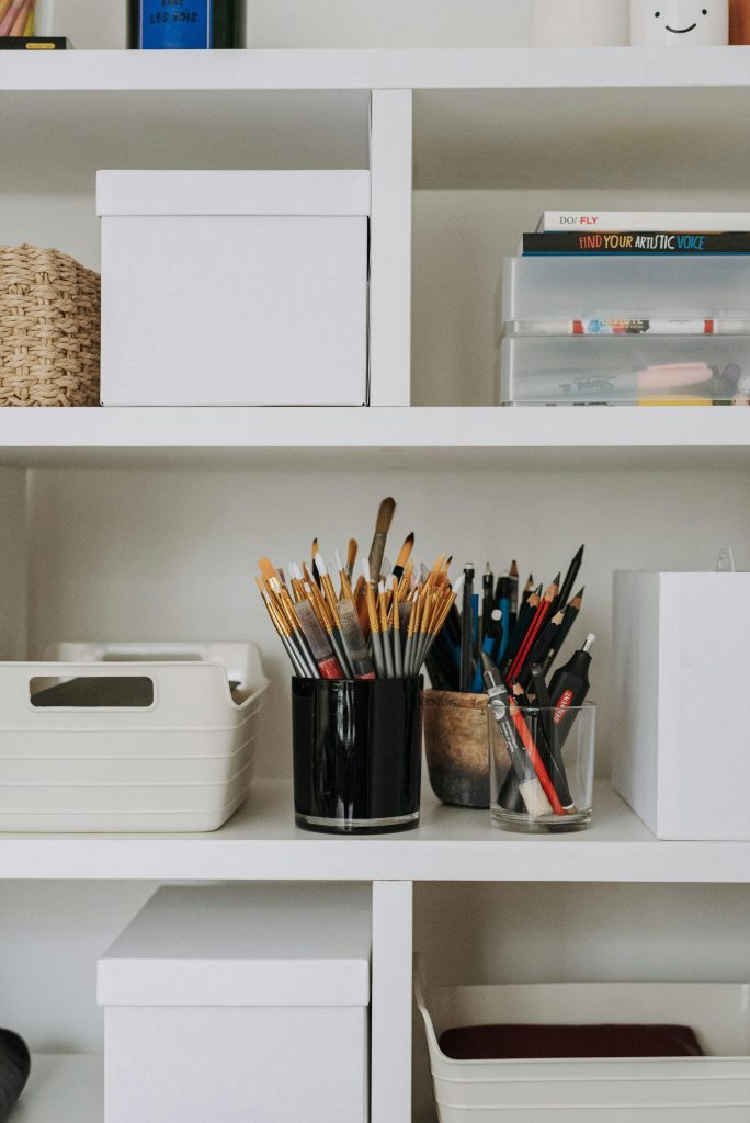 Artistic workspace with organized supplies on white shelves, perfect for creatives.